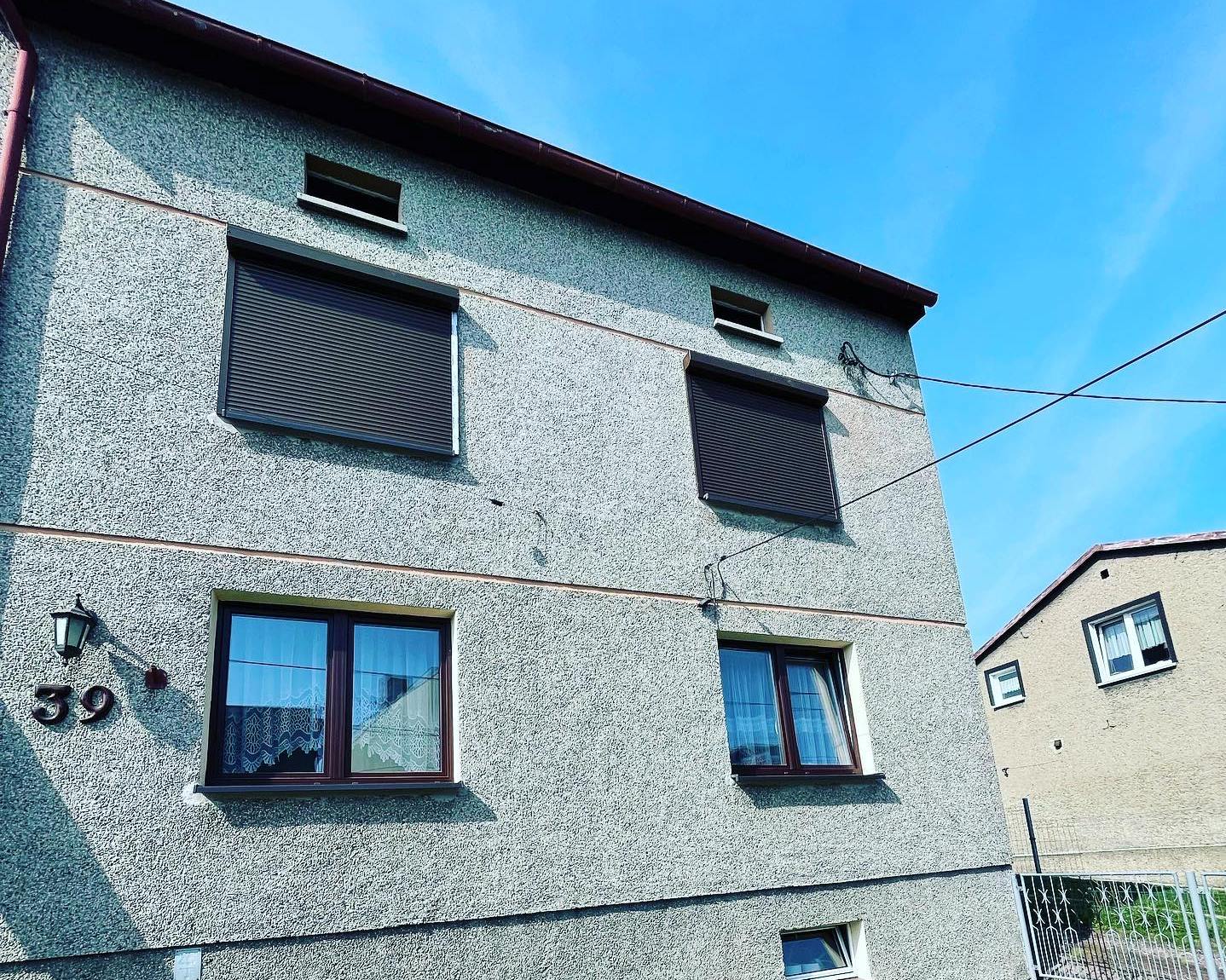 dwie rolety na pierwszym piętrze domu