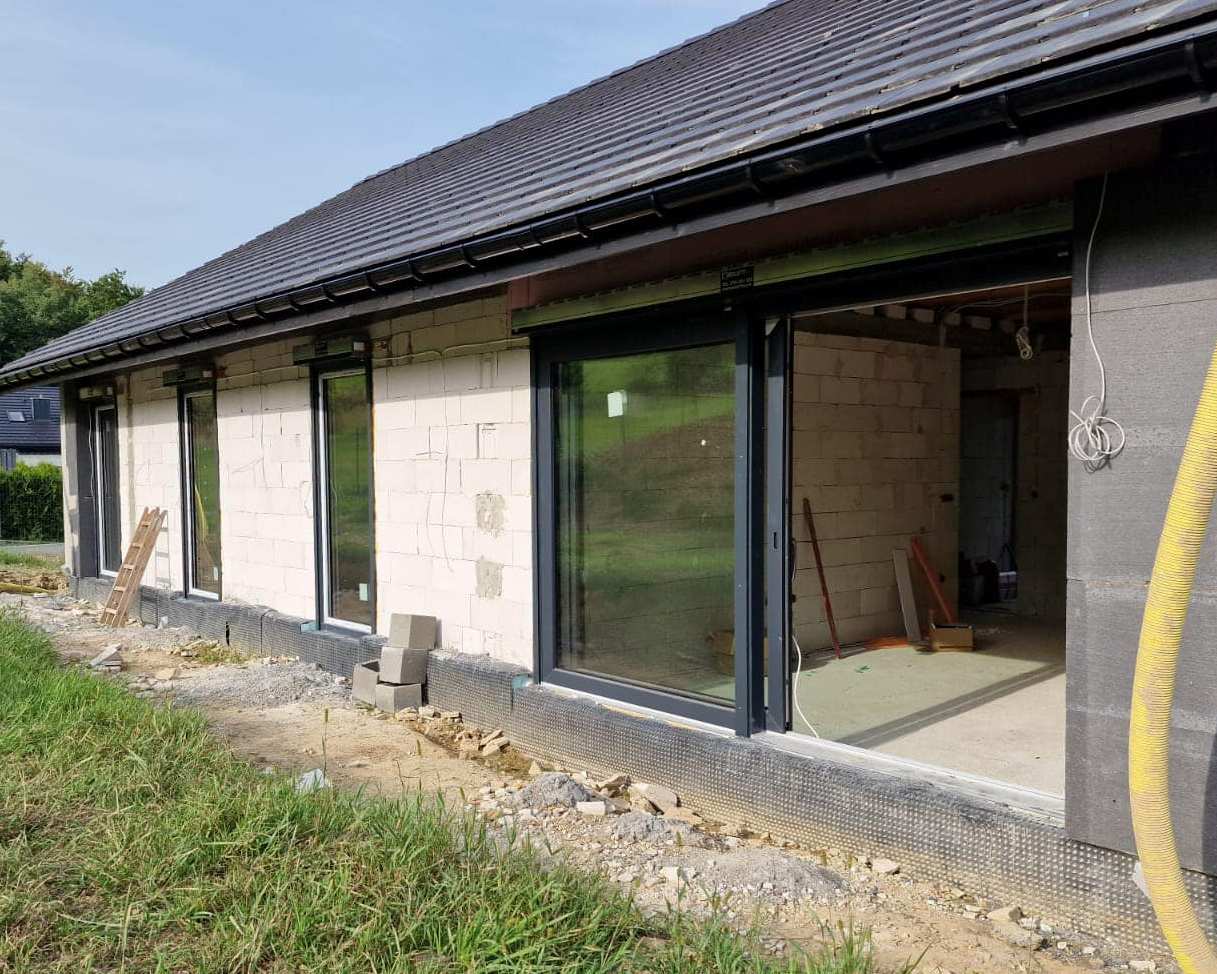 duże otwarte okno z roletą na nieukończonym domu